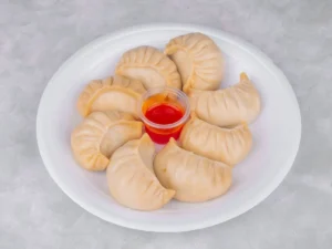 Chicken dumplings with dipping sauce served on a white plate Asian appetizer